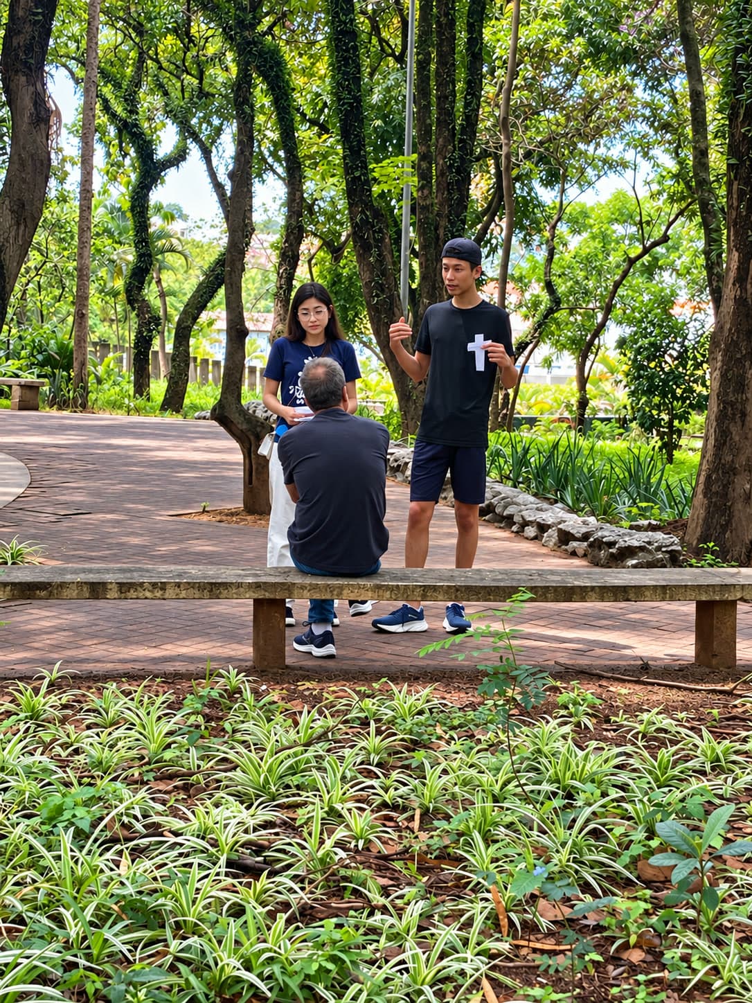 Dois jovens conversam com um homem sentado num banco de praça