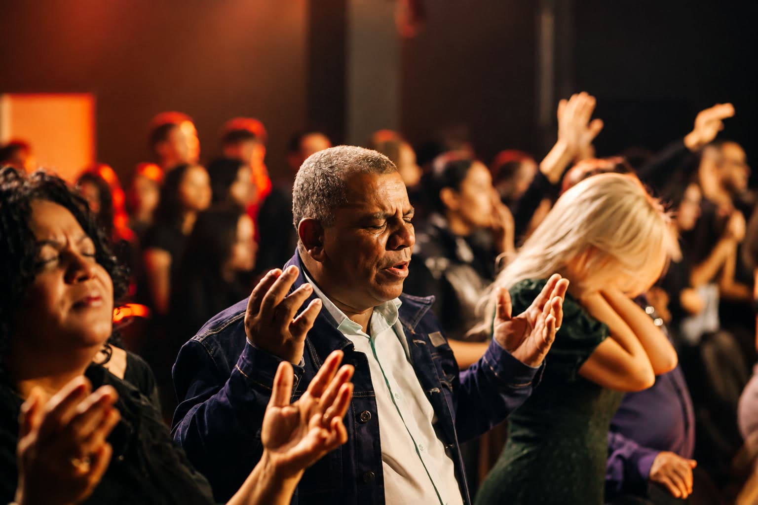 Pessoas de diferentes idades em oração durante um culto